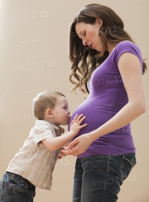 Portrait of boy (2-3) kissing pregnant mother's belly. Photo: Mike Kemp