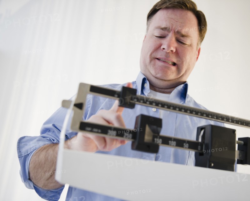 Man on weight scales. Photo : Jamie Grill Photography