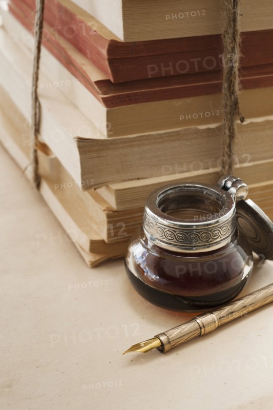 Close up antique ink well, pen and books.