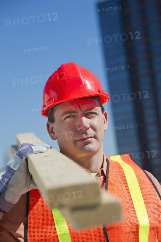 Construction worker carrying planks.