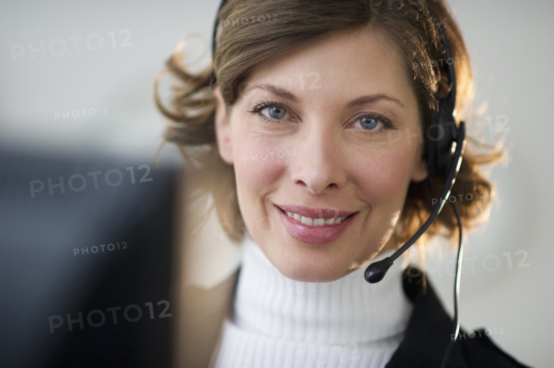 Portrait of smiling woman with headset in customer service office.