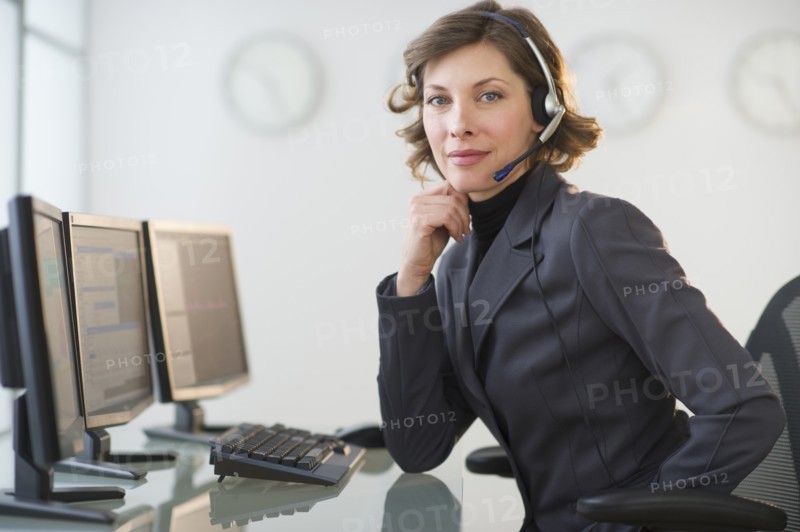 Portrait of smiling woman with headset in customer service office.