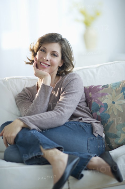 Portrait of smiling woman sitting on sofa.
