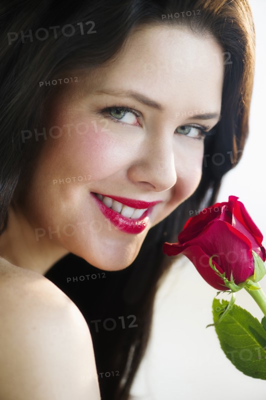 Studio shot of woman smelling red rose.