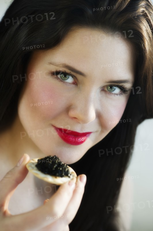 Portrait of young woman eating caviar snack.