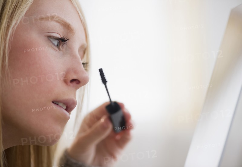 Young woman applying mascara. Photo: Jamie Grill Photography