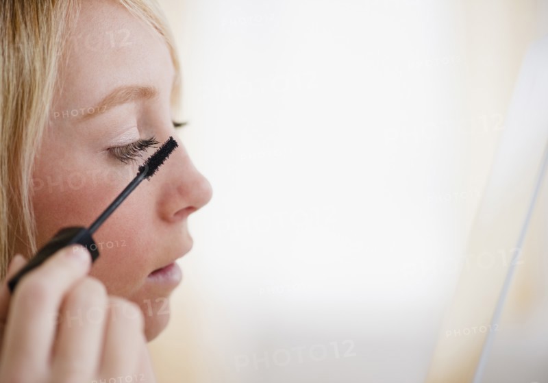 Young woman applying mascara. Photo: Jamie Grill Photography