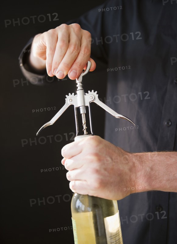 Man opening wine bottle, close-up of hands. Photo : Jamie Grill Photography