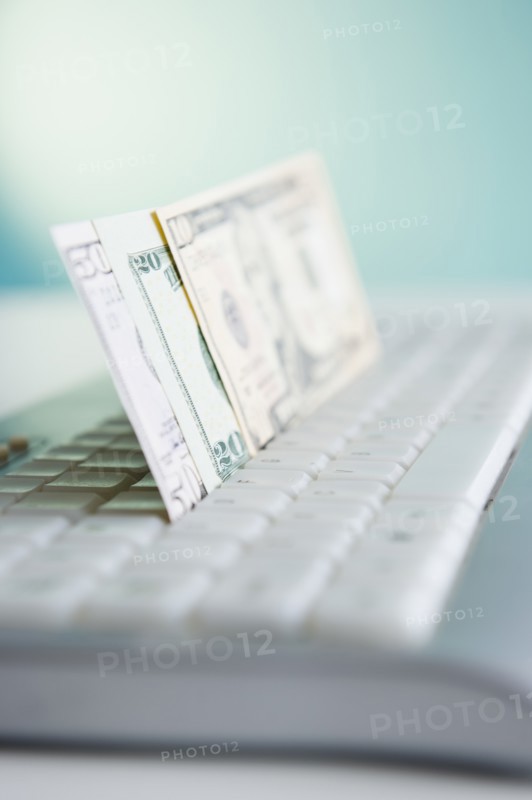 Studio shot of banknotes in computer keyboard. Photo : Jamie Grill Photography