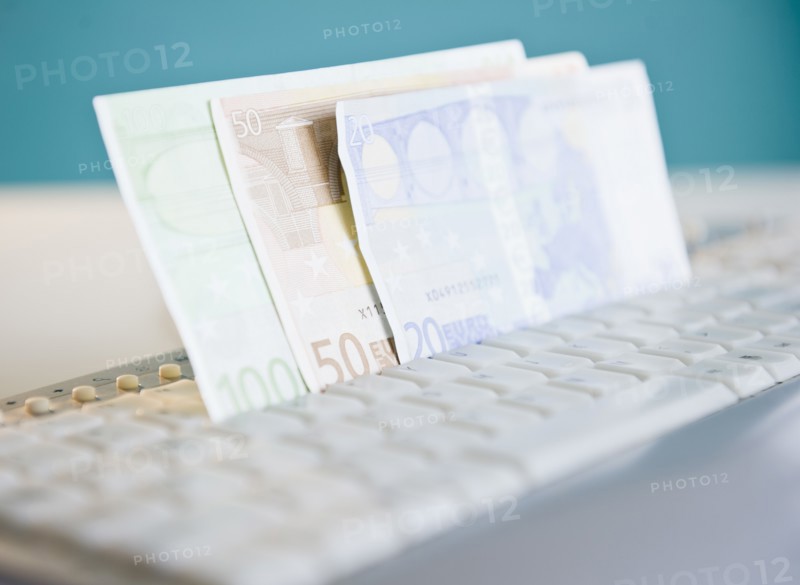 Studio shot of banknotes in computer keyboard. Photo: Jamie Grill Photography