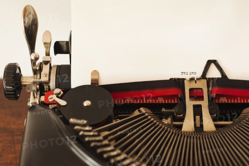 Close up of antique typewriter with "the end" print on page.