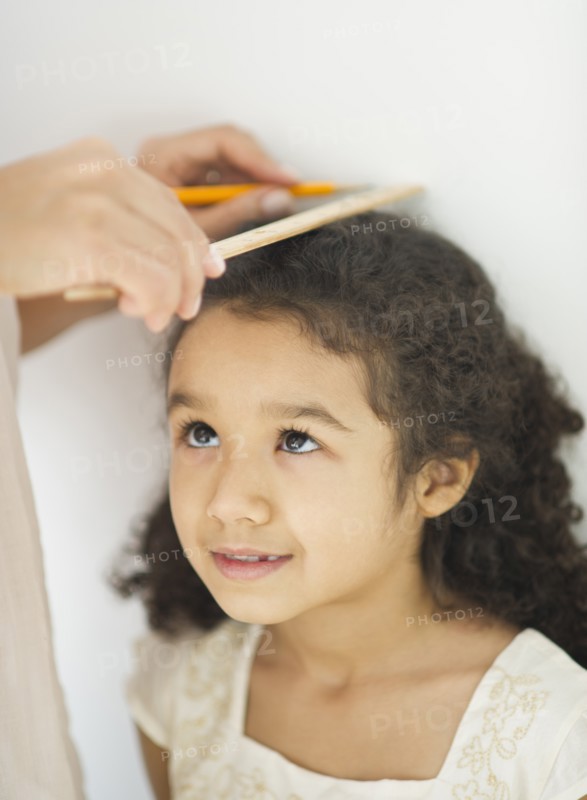 Mother measuring daughter (6-7).