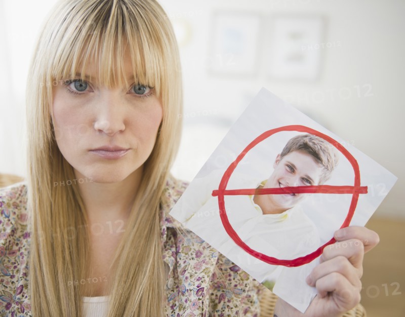 Young woman holding photograph of ex-boyfriend. Photo : Jamie Grill Photography
