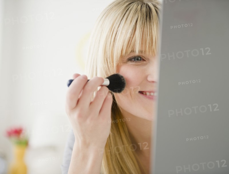 Young woman applying blush. Photo : Jamie Grill Photography