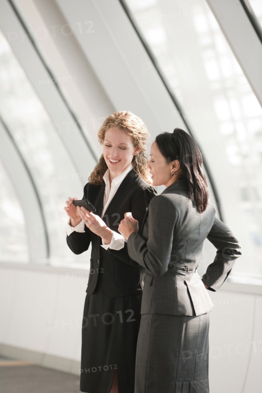 Businesswomen looking at cell phone. Photo : Mark Edward Atkinson