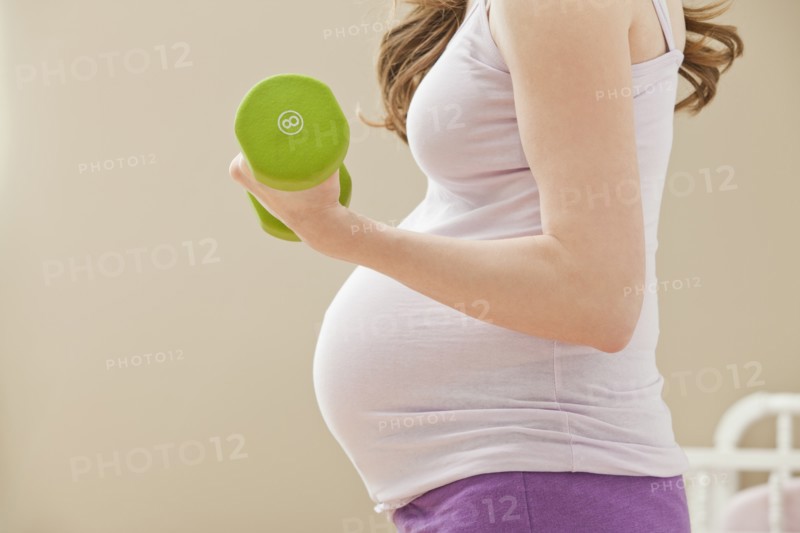 Young pregnant woman excercising with dumbbells. Photo: Mike Kemp