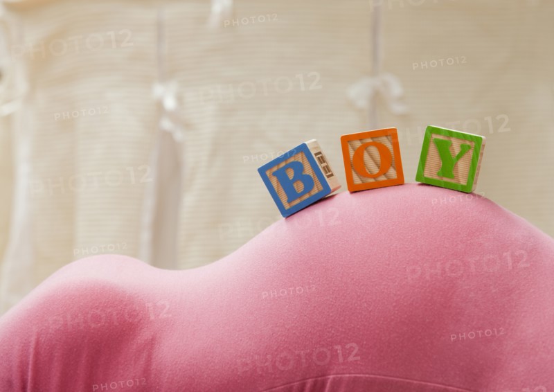 Wooden blocks with letters on pregnant woman's belly, reading as boy. Photo : Mike Kemp
