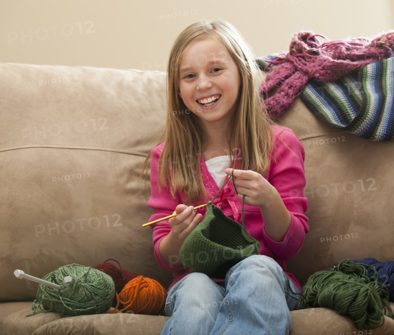 Cheerful girl (8-9) knitting woolly hat. Photo: Mike Kemp