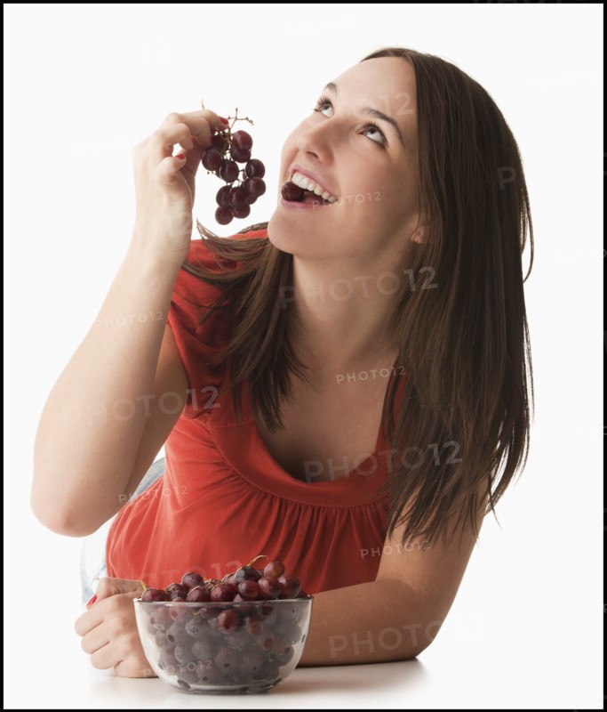 Young woman eating grapes. Photo : Mike Kemp