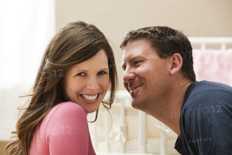Young pregnant woman about to be kissed by mid adult man. Photo: Mike Kemp