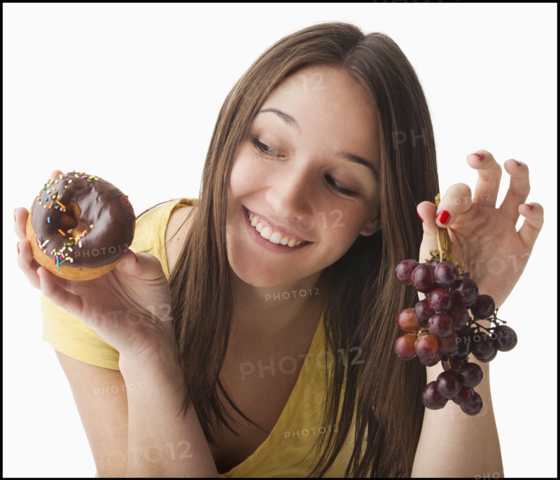 Young woman holding grapes and doughnut. Photo: Mike Kemp