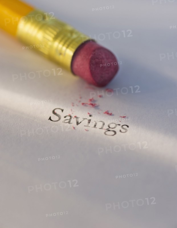 Studio shot of pencil erasing the word savings from piece of paper. Photo : Daniel Grill