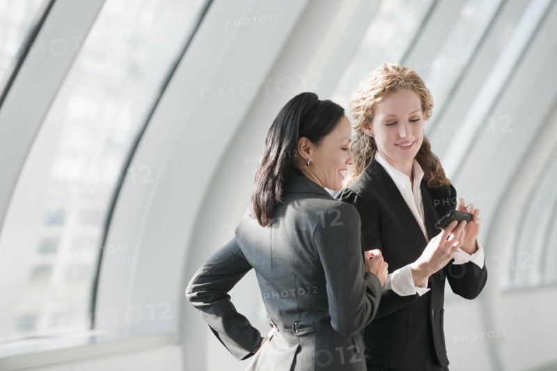 Businesswomen looking at cell phone. Photo : Mark Edward Atkinson