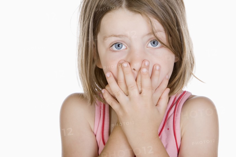 Studio portrait of girl (6-7) covering mouth. Photo: Justin Paget