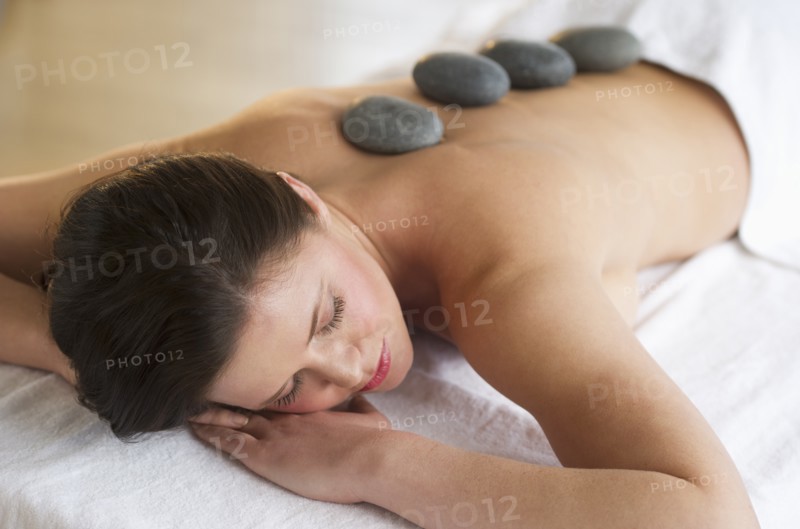 Woman receiving hot stone therapy.