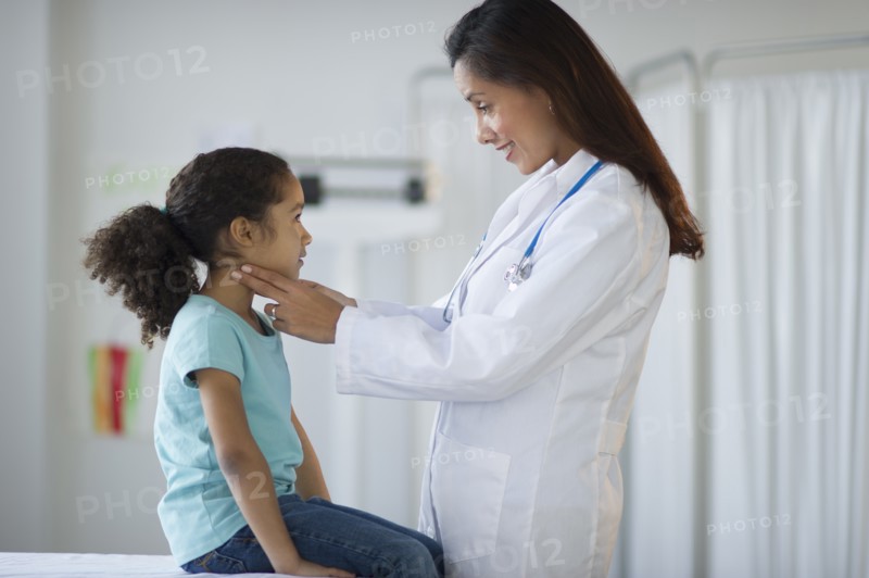Female pediatrician examining girl (6-7) in doctor's office.