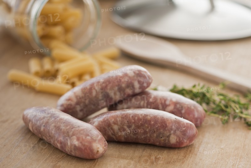 Raw sausage and pasta on kitchen table.