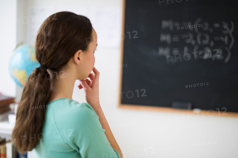 Teenage girl (14-15) looking at blackboard.