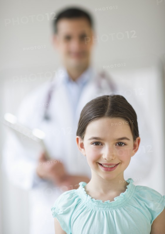 Portrait of girl (8-9), with doctor behind.
