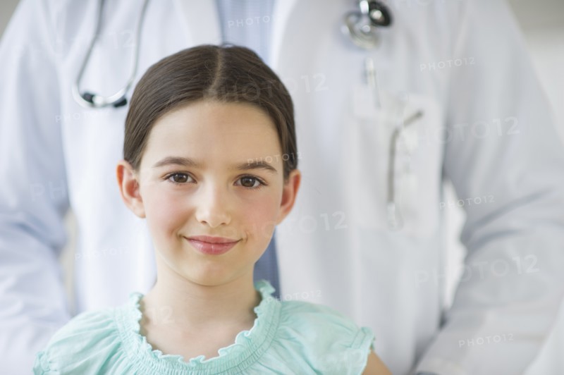 Portrait of girl (8-9), with doctor behind.