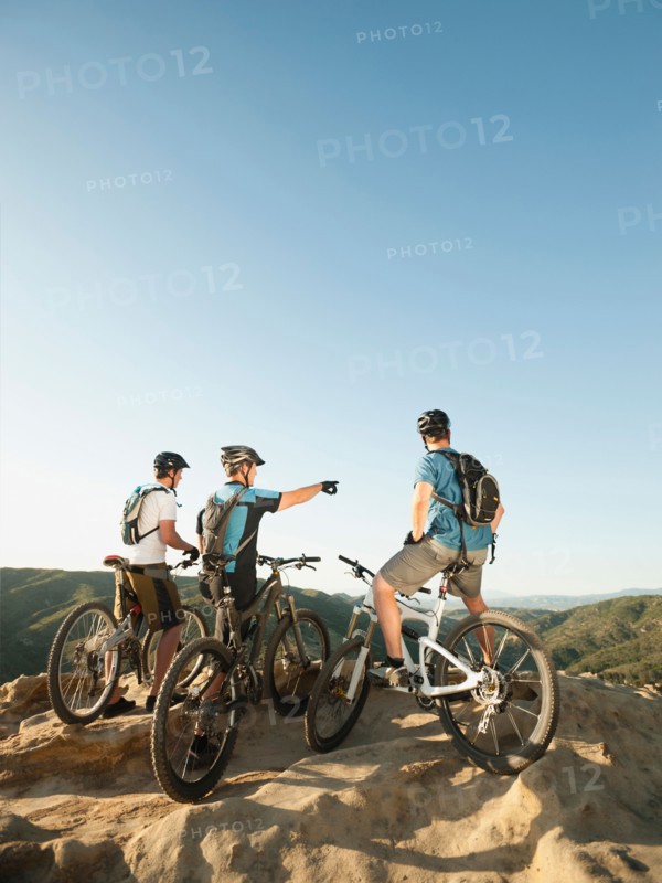 USA, California, Laguna Beach, Two bikers on hill looking at view.