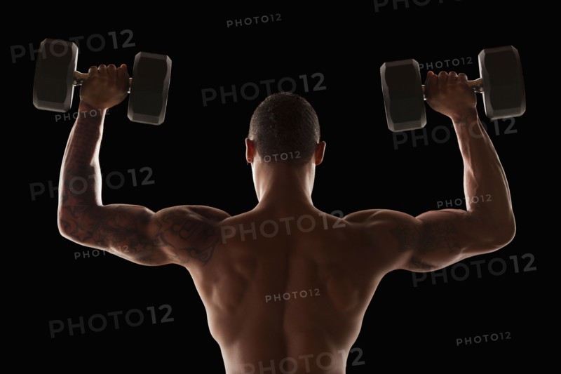 Rear view of muscular man exercising with dumbbells. Photo : Mike Kemp