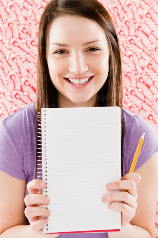Portrait of smiling young woman holding blank notebook. Photo : Jamie Grill Photography