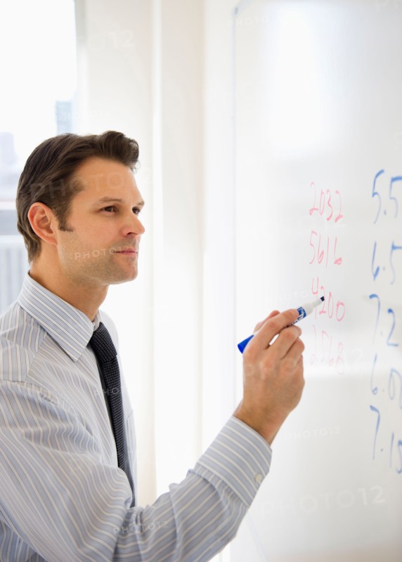 Businessman writing on whiteboard.