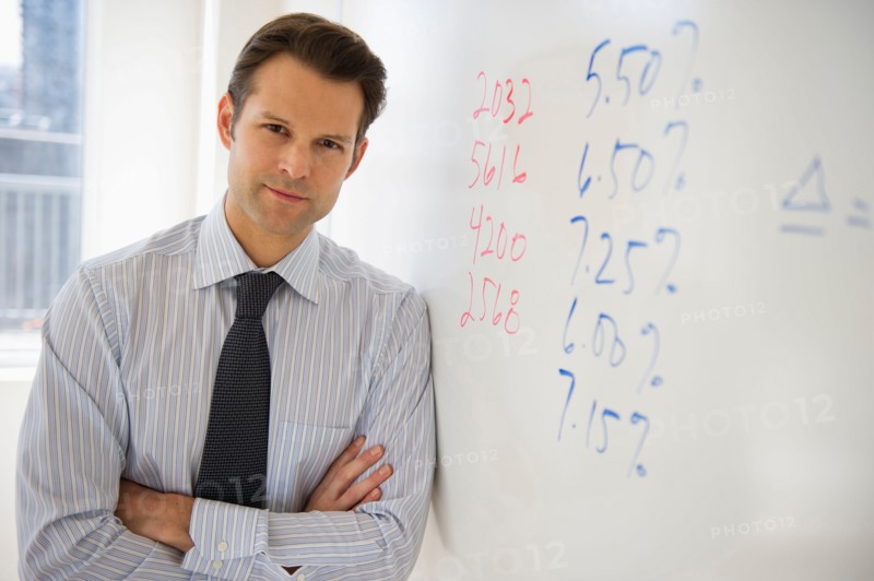 Portrait of businessman leaning against whiteboard.