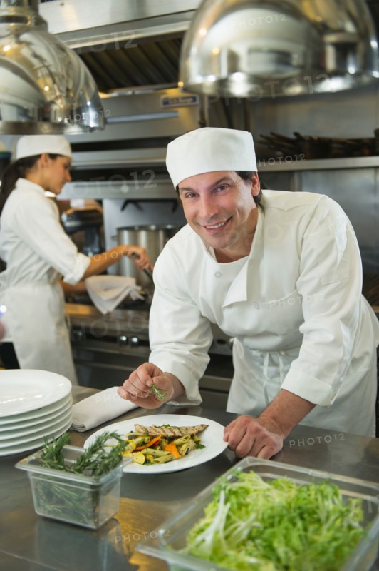 Chef and cook preparing food in commercial kitchen.