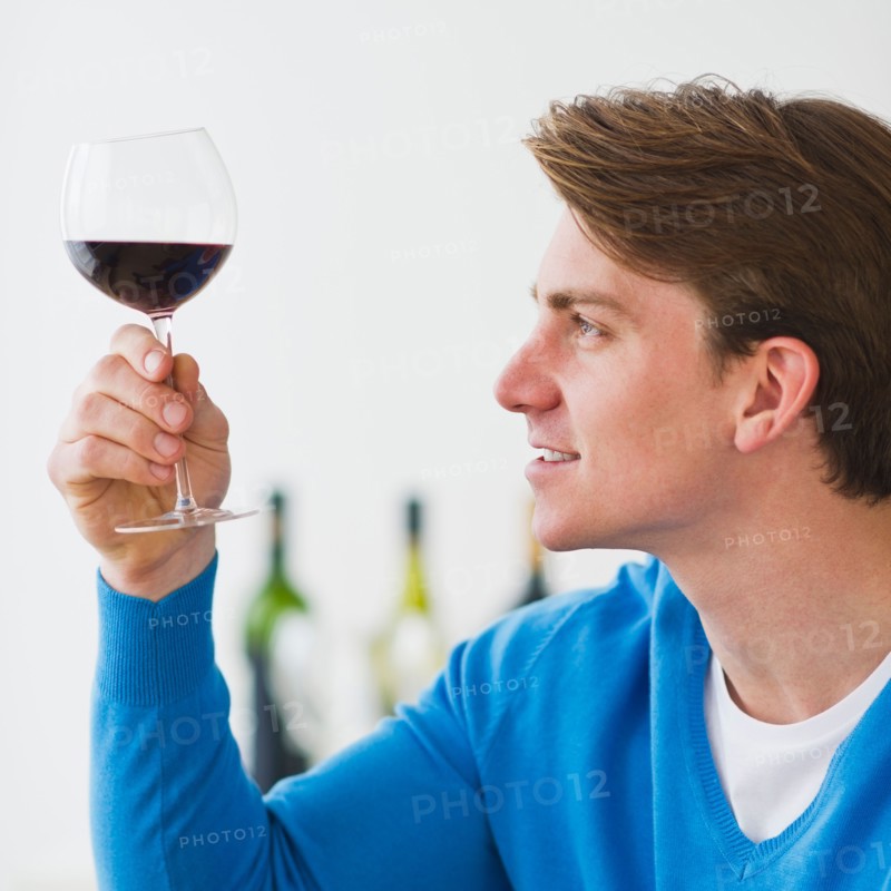 Young man examining red wine. Photo : Daniel Grill