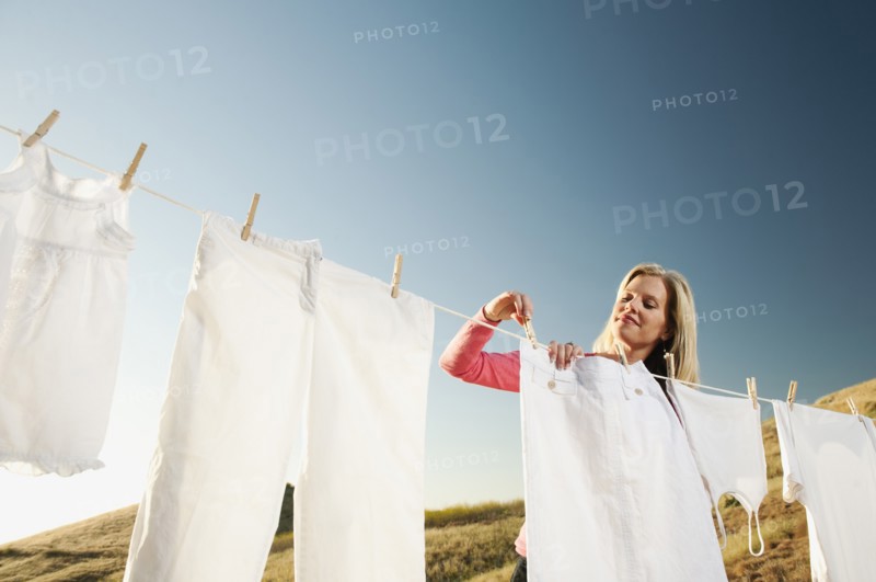 Woman hanging laundry on clothesline .