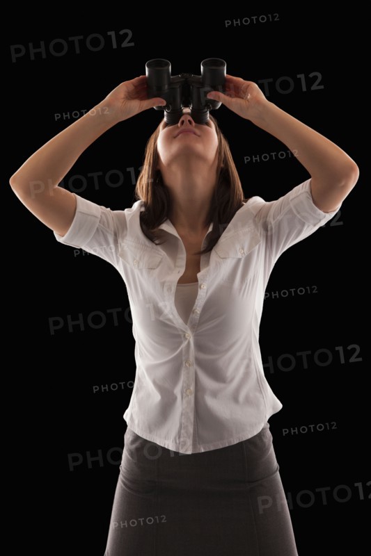 Young attractive businesswoman looking through binoculars. Photo : Mike Kemp