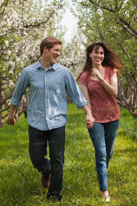 USA, Utah, Provo, Young couple walking through orchard. Photo : Mike Kemp