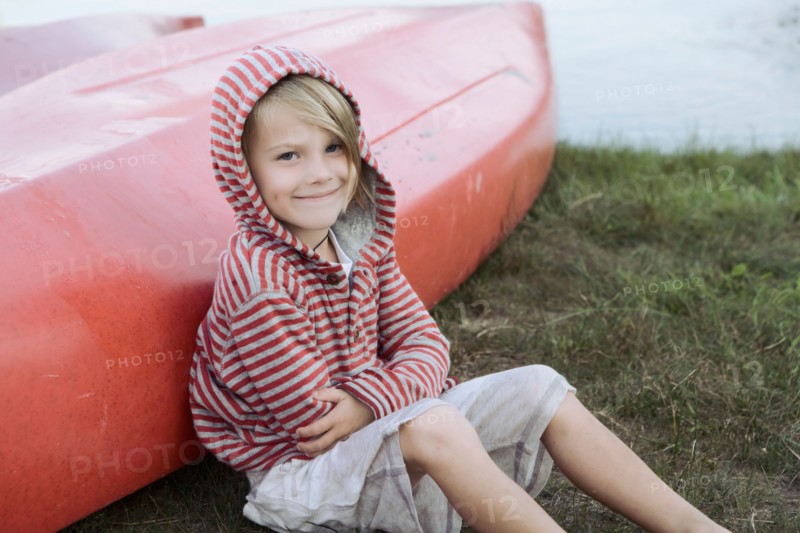 Portrait of boy (4-5) sitting by canoe. Photo : King Lawrence