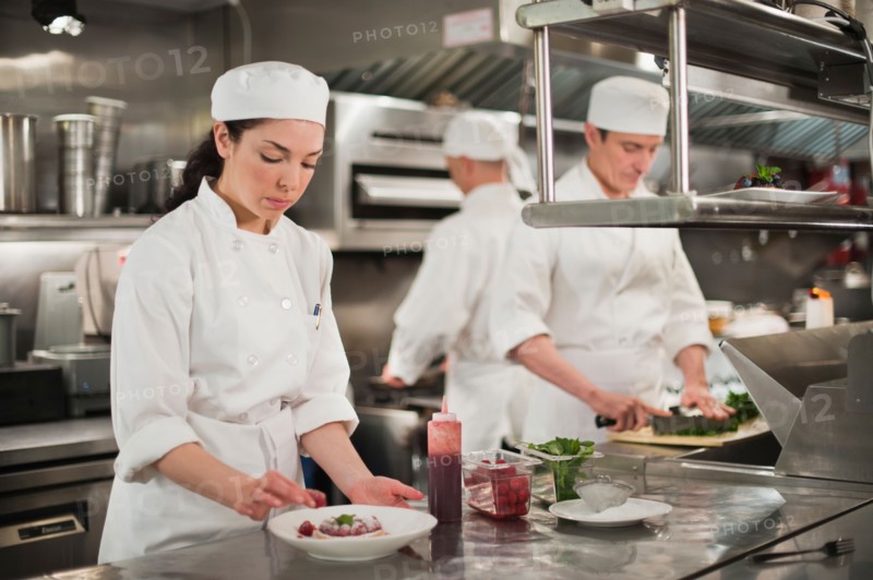 Chefs preparing food in kitchen.