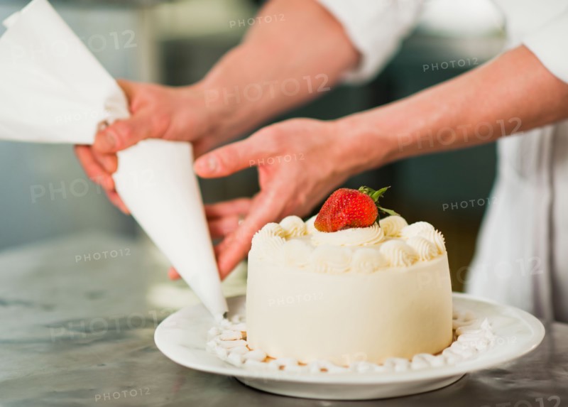 Pastry chef decorating cake.