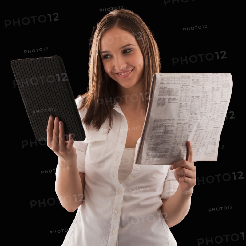 Young attractive businesswoman comparing financial results with financial column in newspaper. Photo : Mike Kemp