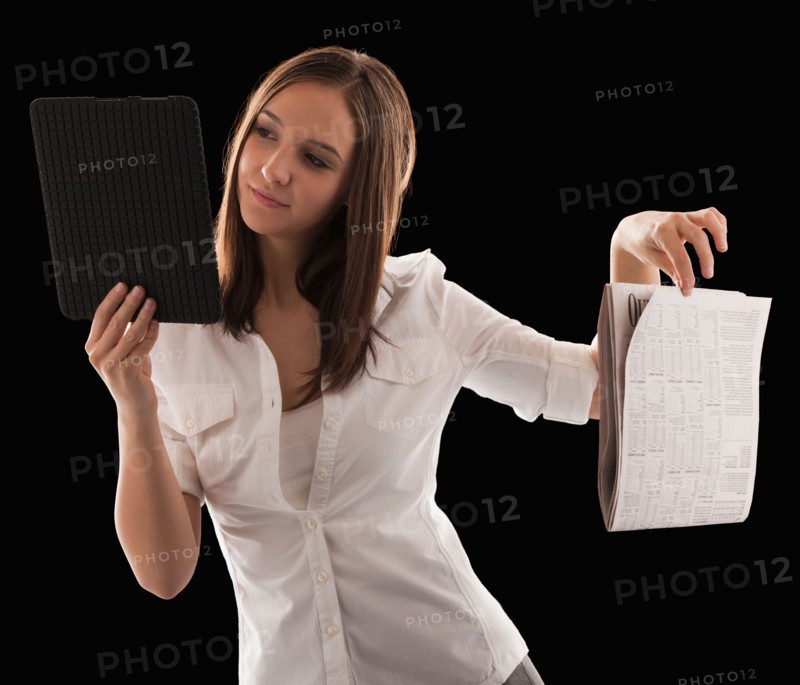 Young attractive businesswoman comparing financial results with financial column in newspaper. Photo : Mike Kemp