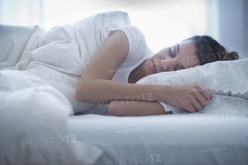 Happy young woman sleeping in bed.